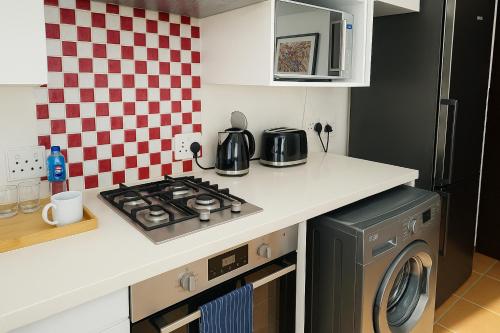 a kitchen with a stove and a washing machine at Lipizzaner Lodge - Kyalami, Midrand in Kyalami
