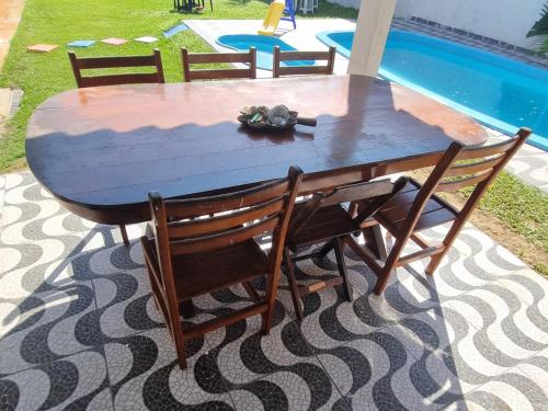 Una mesa de madera con cuatro sillas alrededor junto a una piscina. en Hostel Sepumpá Sepápum, en Itanhaém