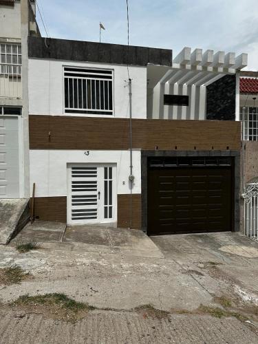 a white and brown house with two garage doors at Casa muy cómoda de 2 pisos en zona muy tranquila in Media Fanega