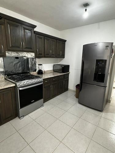 a kitchen with wooden cabinets and a stainless steel refrigerator at Casa muy cómoda de 2 pisos en zona muy tranquila in Media Fanega