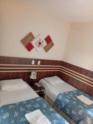 a room with two beds and pictures on the wall at San Marino Hotel in São José dos Campos