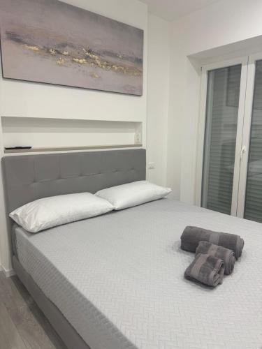a bedroom with a white bed with a painting on the wall at Rebecca s Apartments Deluxe Family Sea View Anzio in Anzio
