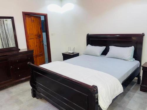 a bedroom with a large bed with a wooden headboard at Tropical Getaway - Rooftop Apartment in Sukuta