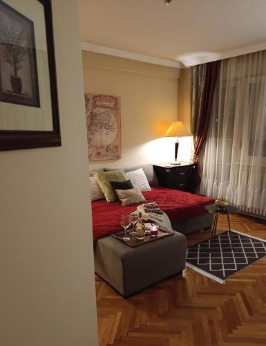 a bedroom with a bed with a red blanket and a table at Harmony II downtown Sabac in Šabac