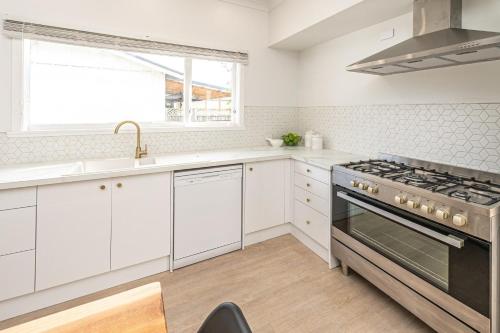 a kitchen with white cabinets and a stove at Luxury Living Central College Estate Springvale in Whanganui