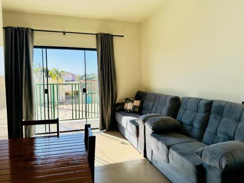 a living room with a couch and a sliding glass door at Nalevaiko- Apartamento com Varanda e Ar Condicionado in Sinop