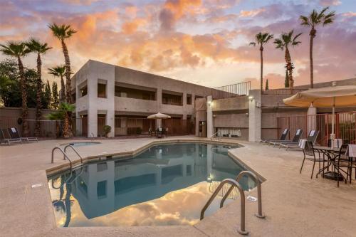 a swimming pool in front of a building with palm trees at Best Western InnSuites Tucson Foothills Hotel & Suites in Tucson