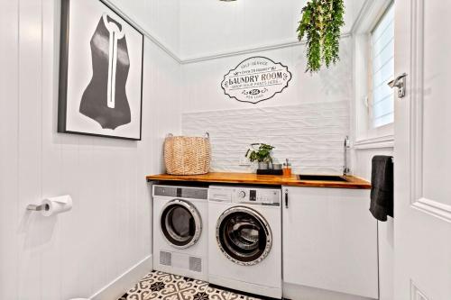 a white laundry room with a washer and dryer at The Manor Bargara in Bargara