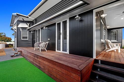 a house with a deck with green grass at The Manor Bargara in Bargara