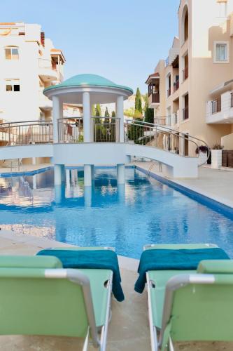 a swimming pool with chairs next to a building at Stylish Studio with Pool Access, Free parking, Paphos center - Work Friendly in Paphos City