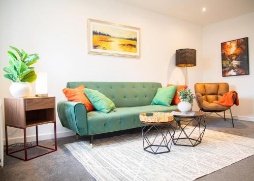 a living room with a green couch and two chairs at Premium Contractors House near M6 J3 & CBS Arena in Coundon