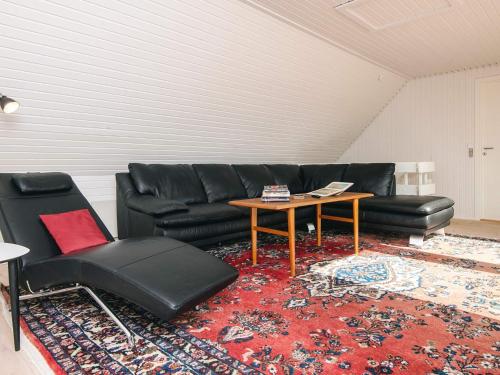 a living room with a black leather couch and a table at 4 star holiday home in Nørre Nebel in Nørre Nebel