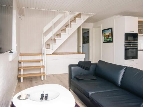a living room with a black leather couch and stairs at 4 star holiday home in Nørre Nebel in Nørre Nebel