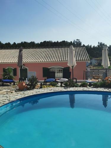 a swimming pool in front of a house with umbrellas at Casa Picamilho in Porto de Mós