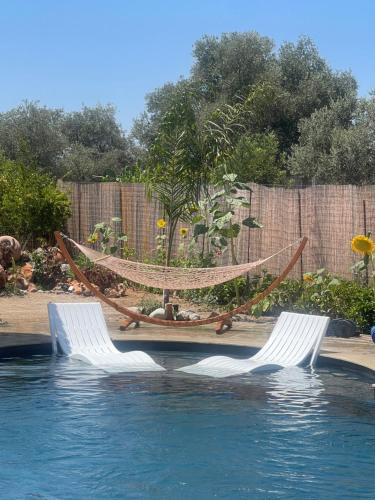 two chairs and a hammock next to a swimming pool at La casa di pantelis with Luxury Pool in Archangelos