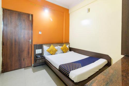 a bedroom with a bed and a wooden door at Hotel O SK Lodge in Kumbalgod