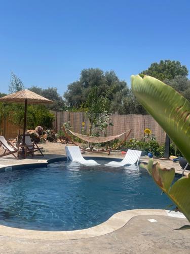 a swimming pool with two chairs and an umbrella at La casa di pantelis with Luxury Pool in Archangelos