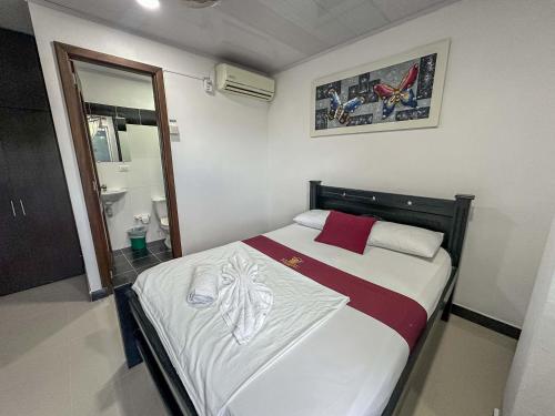 a small bedroom with a bed with red and white sheets at HOTEL COLONIAL santorini colombiano in Doradal