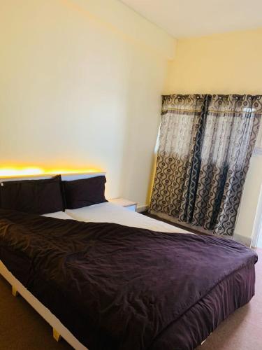 a bedroom with a large bed and a window at Malika Kohsar Hotel Murree in Murree