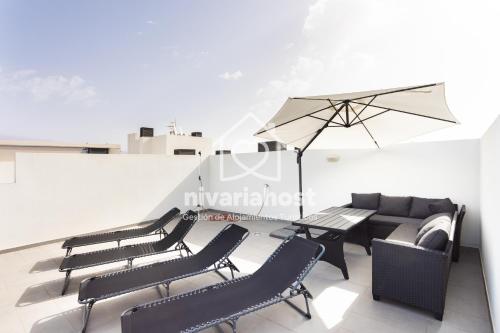 a group of chairs and a table with an umbrella at The Penthouse La Tejita, by Nivariahost in La Tejita