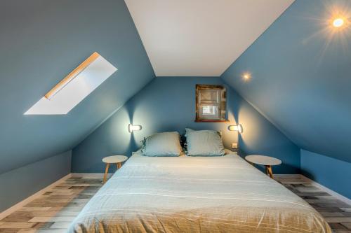 a blue room with a bed with two tables at Le gîte de Saint Mathieu, longère pleine de charme au bout du monde ! jacuzzi extérieur vue sur la campagne, salle de billard in Plougonvelin