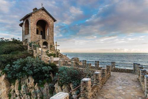a building on a hill next to the ocean at Oasi Relax Alassio Riviera in Alassio
