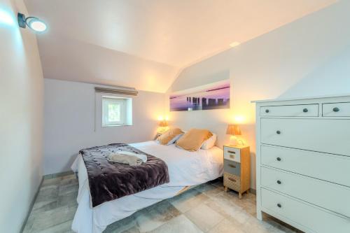 a bedroom with a bed and a dresser with two lamps at Le gîte de Saint Mathieu, longère pleine de charme au bout du monde ! jacuzzi extérieur vue sur la campagne, salle de billard in Plougonvelin