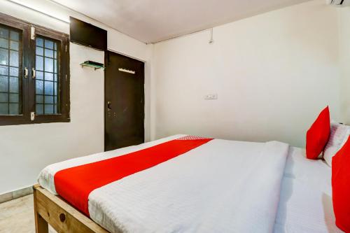 a bedroom with a bed with red and white sheets at Hotel O Dhruv Inn in Izatnagar