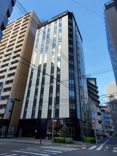 a tall building with glass windows on a city street at Tokyu Stay Kamata - Tokyo Haneda in Tokyo