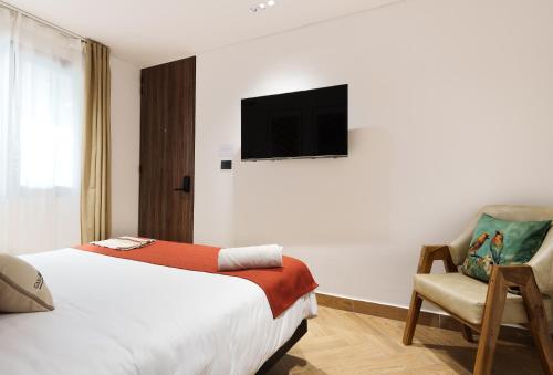 a hotel room with a bed and a tv on the wall at Hotel CASA TAMA in Salento