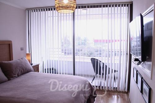 a bedroom with a bed and a large window at Departamento Av. Los Carrera Copiapó Disegni 07 in Copiapó