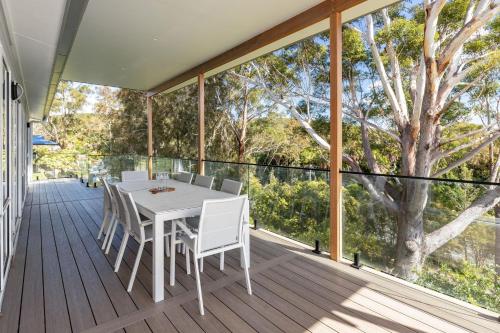 a white table and chairs on a deck with a tree at Bangalow in Elizabeth Beach