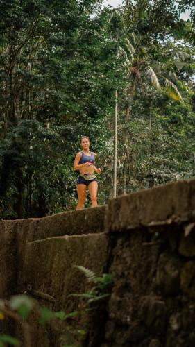 a woman standing on top of a wall at Trails, waterfalls & chill in private jungle lodge in Selemadeg