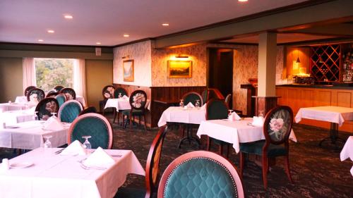 a dining room with white tables and chairs at Waitakere Resort & Spa in Auckland