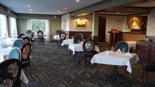 a dining room with white tables and chairs at Waitakere Resort & Spa in Auckland