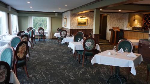 a dining room with white tables and chairs at Waitakere Resort & Spa in Auckland
