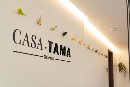 a white wall with a sign on the side of a building at Hotel CASA TAMA in Salento