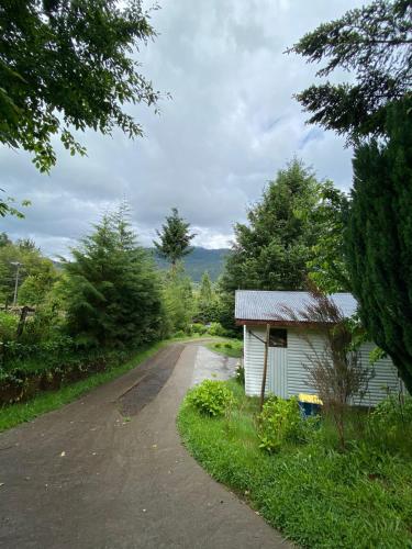 a dirt road next to a small building at Exquisita Cabaña familiar a minutos del Lago Caburgua y Pucón in Caburgua