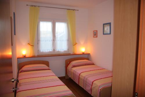twee bedden in een kleine kamer met twee ramen bij Apartment Anethum in Premantura
