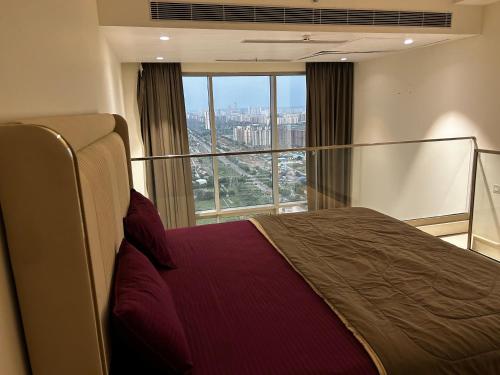 a bedroom with a bed and a large window at Cosy Duplex M3M in Gurgaon