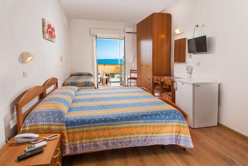a bedroom with a bed and a refrigerator and a kitchen at Hotel Alba Serena in Misano Adriatico