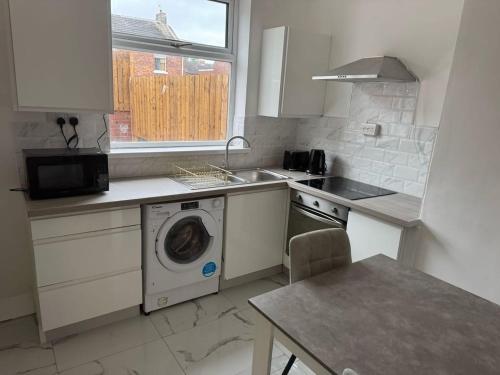 a kitchen with a washing machine and a sink at Wesley Villa in Shildon