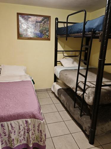 Habitación con 2 literas y suelo de baldosa. en Hospedaje Bugambilias, en Zacatlán