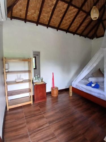 a room with a bed and a wooden floor at Sumatra Cheeky Monkeys Villa, Trekking and Tours in Bukit Lawang