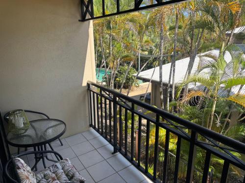 a balcony with a table and a chair and palm trees at Trinity Beach Club Holiday Apartments in Trinity Beach