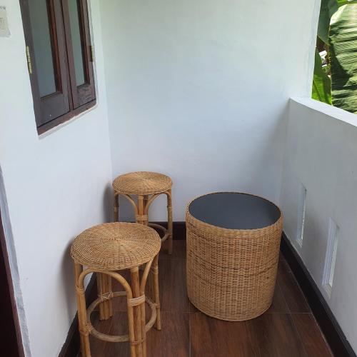 two chairs and two stools sitting next to a wall at Sumatra Cheeky Monkeys Villa, Trekking and Tours in Bukit Lawang