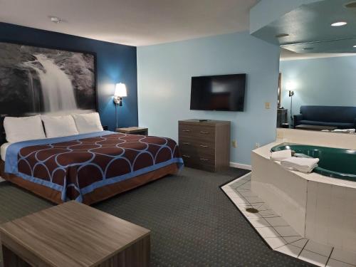 ハドソンにあるRiver Hill Inn & Suitesのベッド、バスタブ、テレビが備わるホテルルームです。