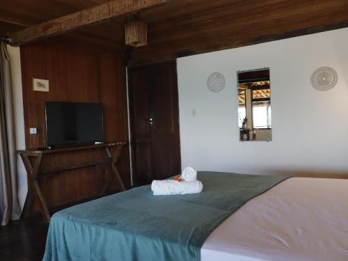a bedroom with a bed with a flat screen tv at Bem Me Quer Casas in Morro de São Paulo