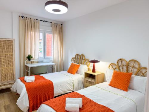 a bedroom with two beds with orange and white at El Rinconín - Tu Casa En Gijón in Gijón