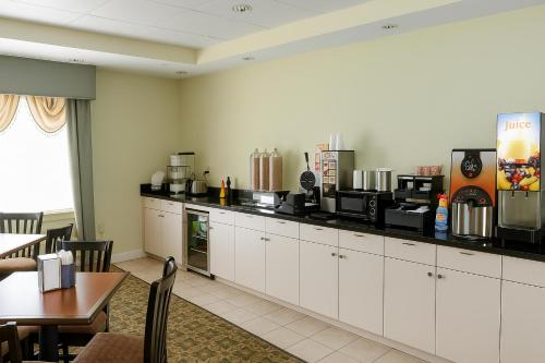 タスカルーサにあるAmbassador Inn & Suites Tuscaloosa University I-20の白いキャビネット、テーブル、カウンター付きのキッチン
